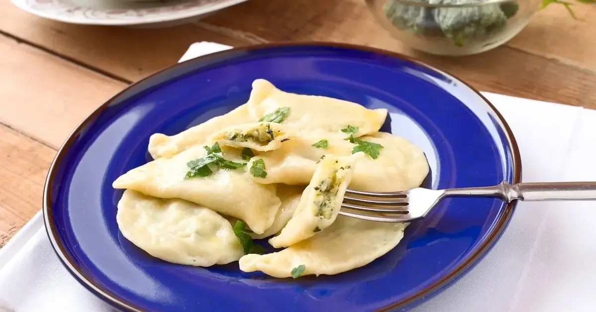 Pierogi ze szpinakiem i serem feta na niebieskim talerzu