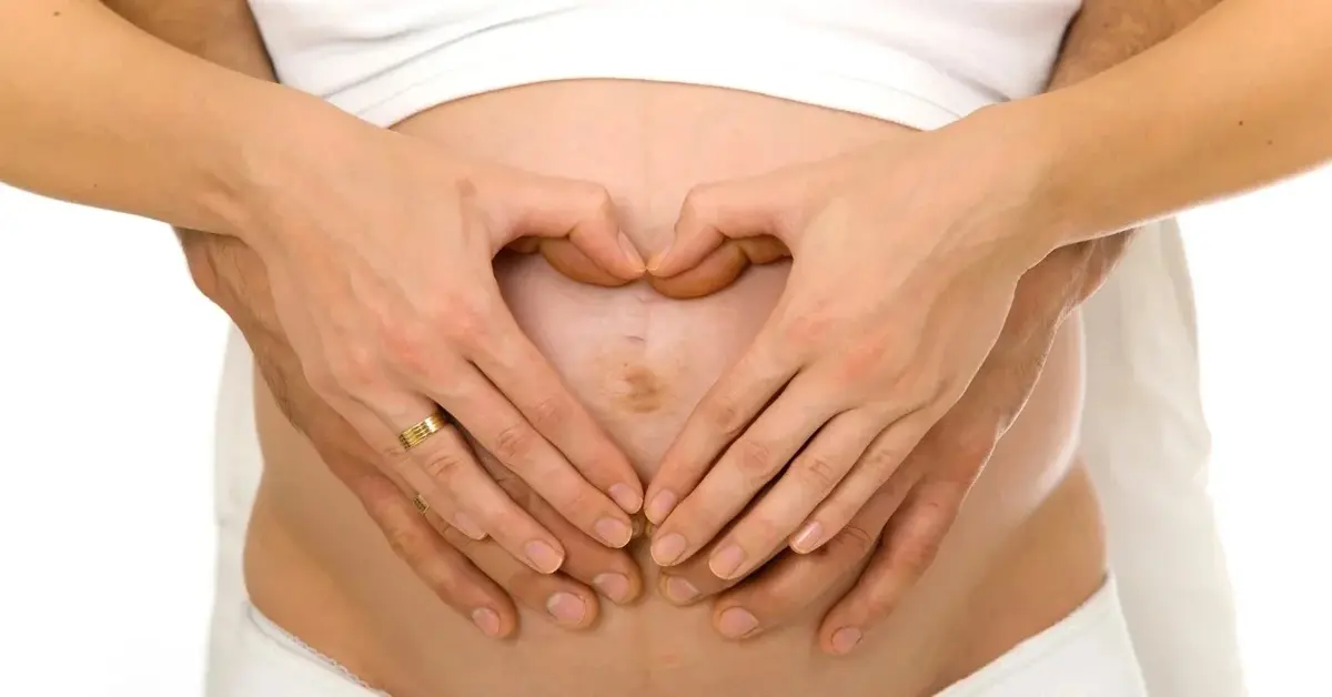 Koibeta w ciąży trzymajaca dłonie na brzuchu