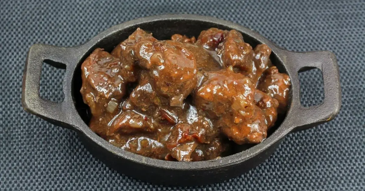 Gulasz z dzika w żeliwnej patelni na ciemnym tle 