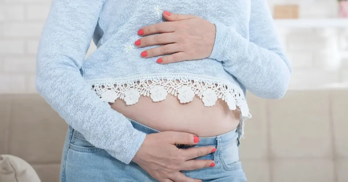 Kobieta w ciąż trzymająca się pod brzuchem rękami