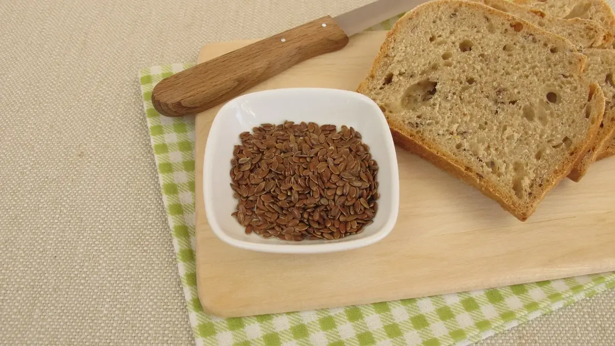 Chlen keto na drewnianej desce. Obok biała miseczka z siemieniem lnianym