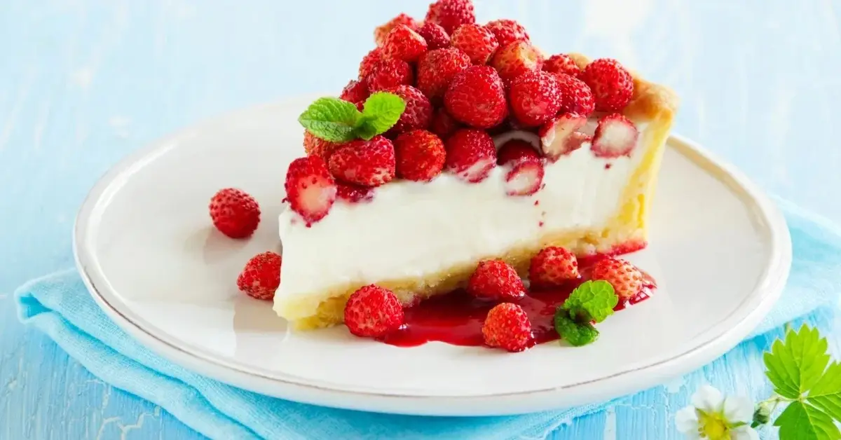 Torcik z bitą śmietaną i serkiem mascarpone i poziomkami na białym talerzyku