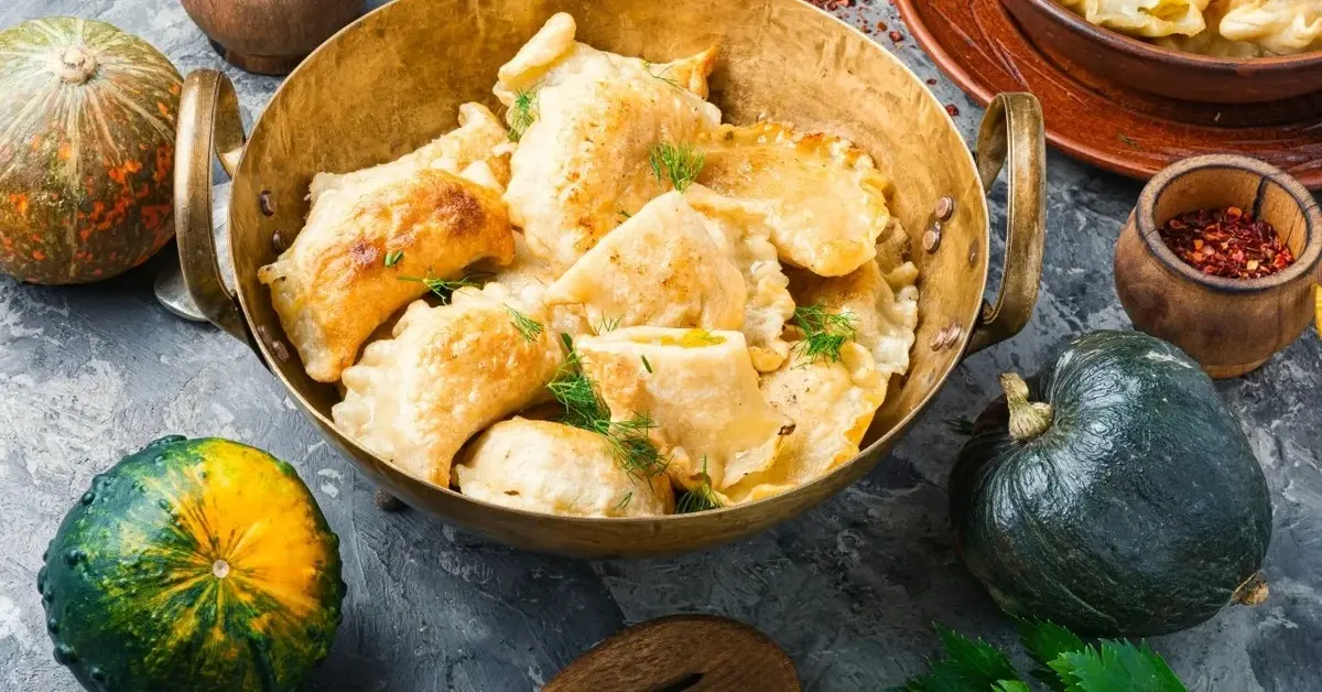 Pierogi z dynią w głębokiej misce, obok dynie w różnych kształtach 