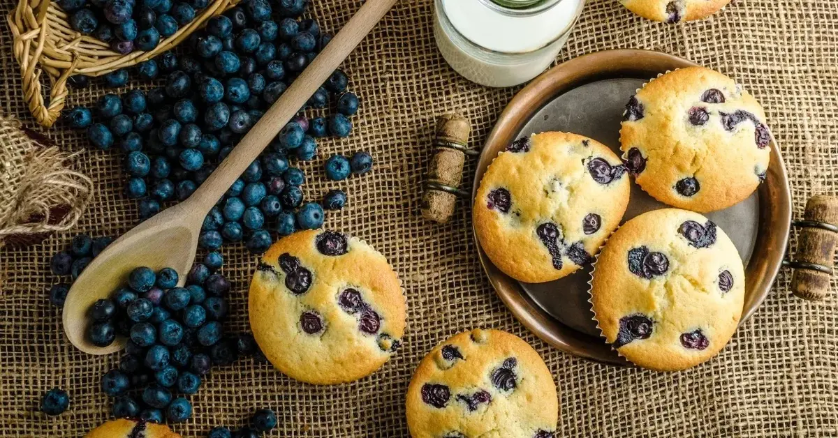 Muffinki z borówkami, obok rozsypane świeże borówki 