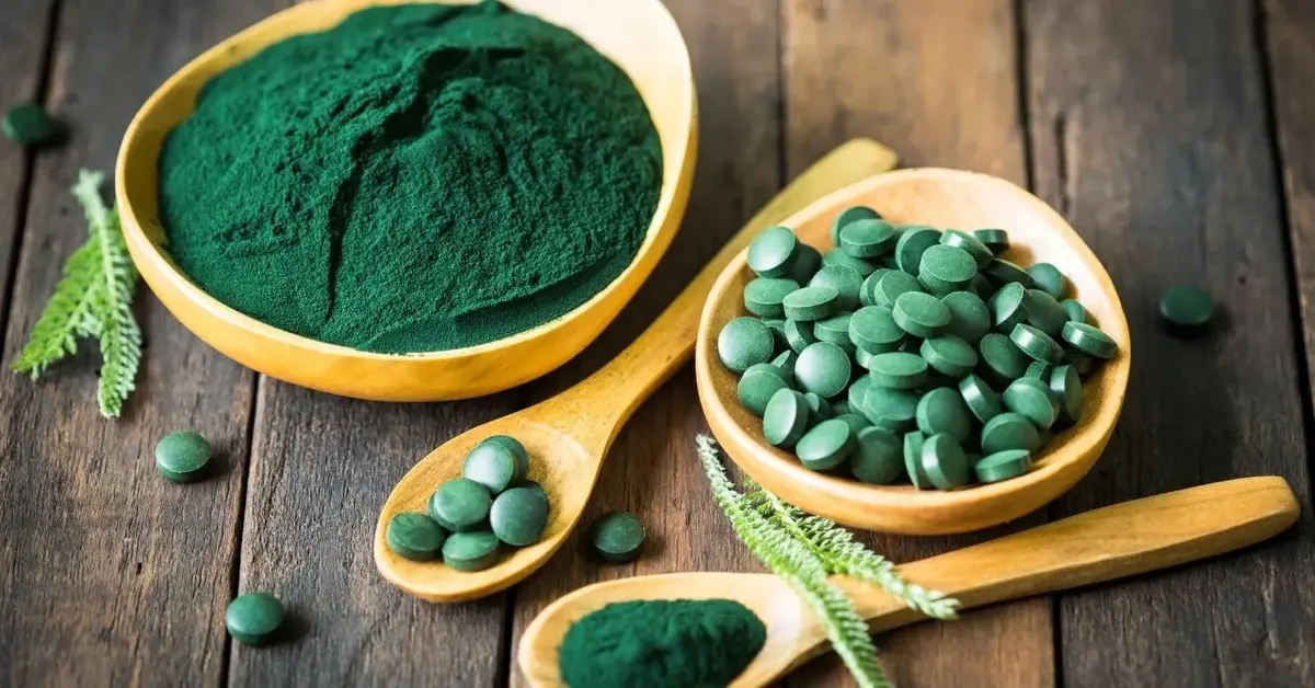 Spirulina w proszku i tabletkach na łyżeczkach i w miseczkach 