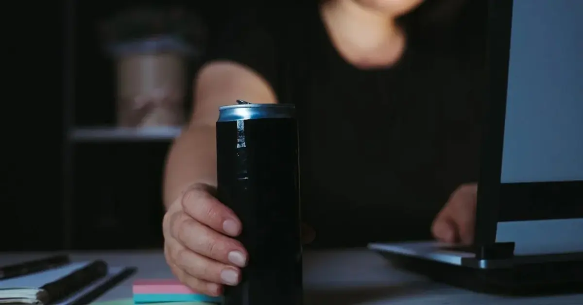 Kobieta pije napój energetyzujący przy komputerze