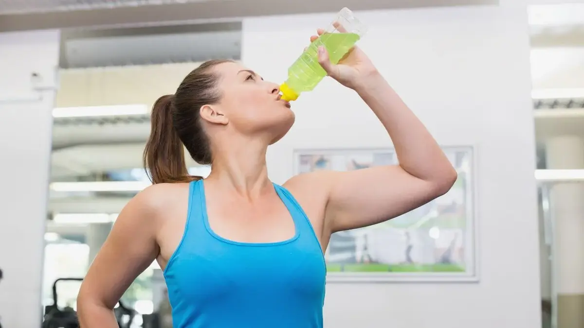 Kobieta po treningu pije napój energetyzujący