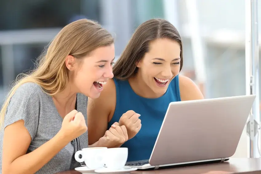 Excited friends finding on line content in a laptop
