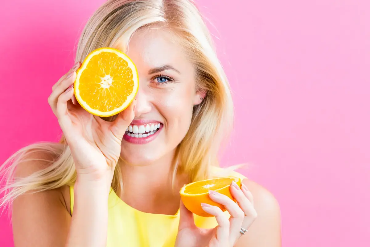 Happy young woman holding orange halves