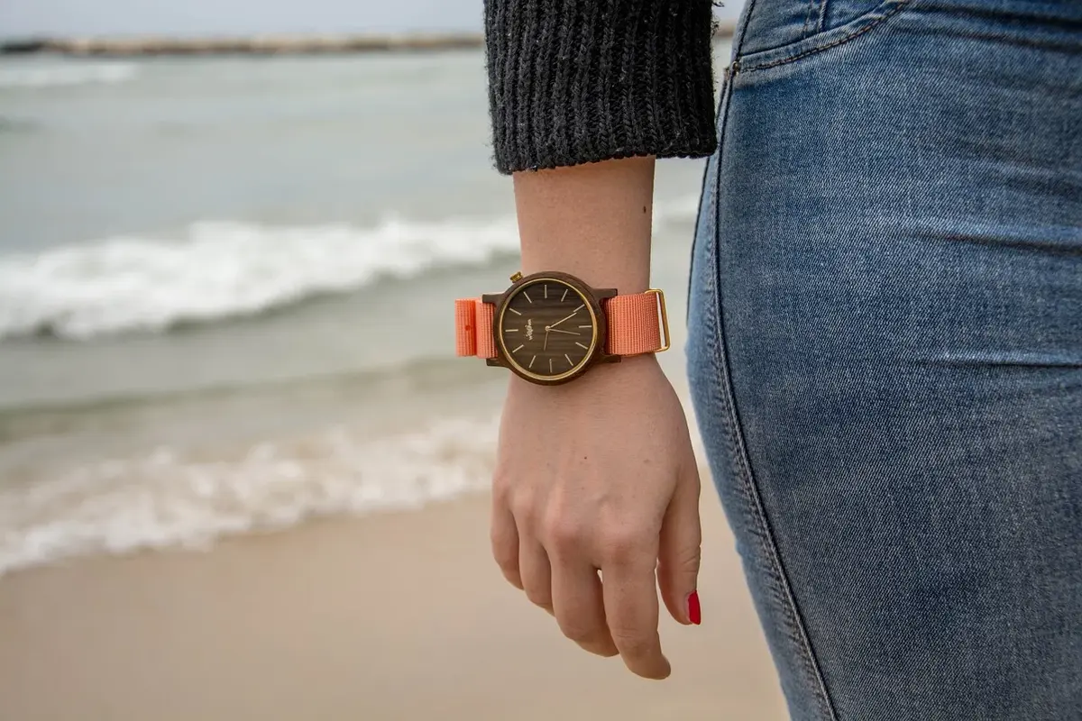 ręka kobiety z modnym zegarkiem na przegubie w tle fale morskie