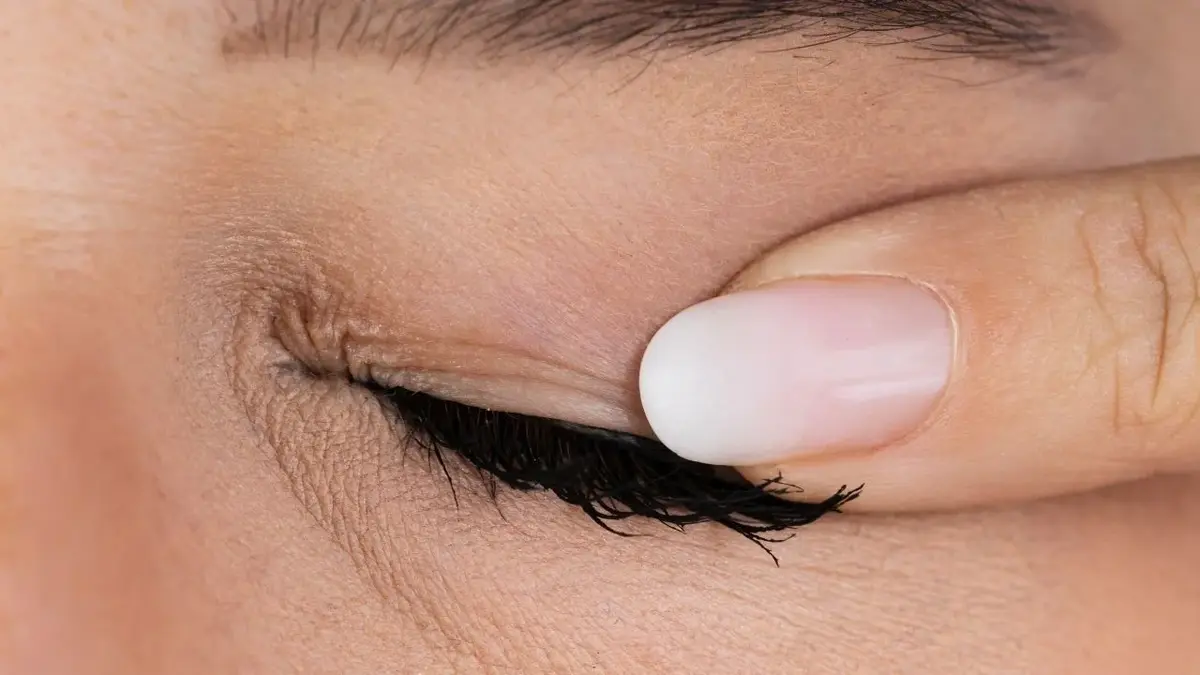 kobiecy palec przyciska linii rzęs na oku