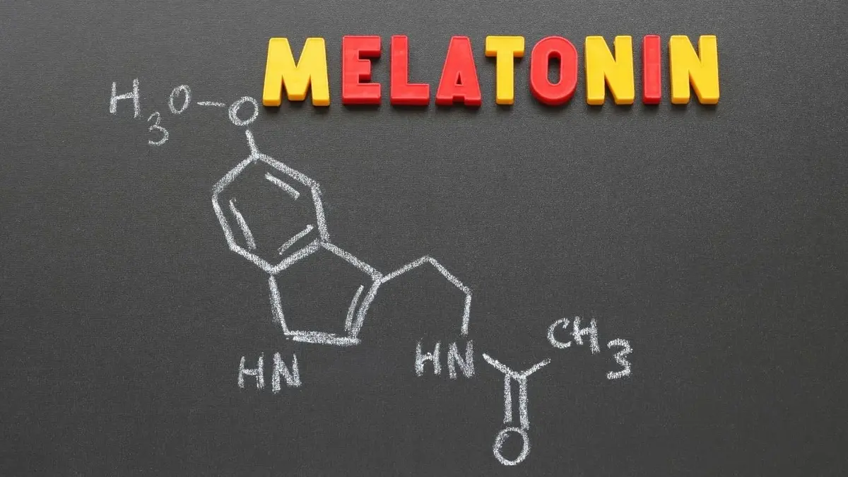 napis melatonina ułożony z czerwonych i żółtych literek na tablicy kredowej