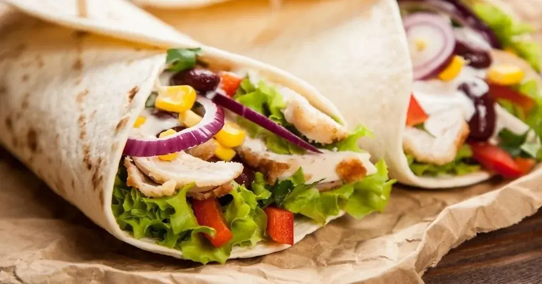 zbliżenie na dwie tortille położone obok siebie z cebulą, sałatą i gyrosem