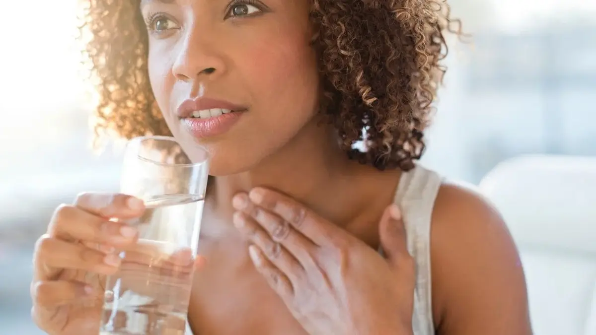 Kobieta trzyma się za gardło