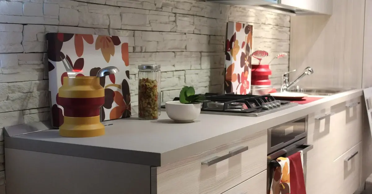 Jasne meble kuchenne z biało-czerwonymi dodatkami w kuchni o białej, ceglanej ścianie