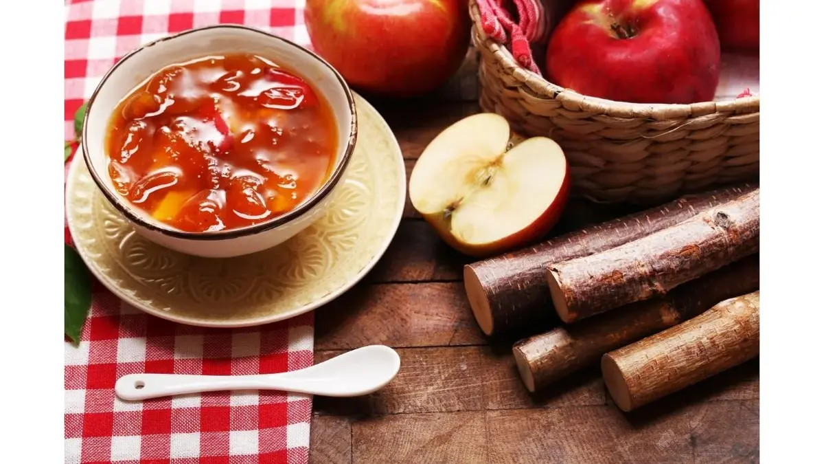 Domowy kisiel jabłkowy w miseczce. Obok łyżeczka, jabłka i kawałki drewna.