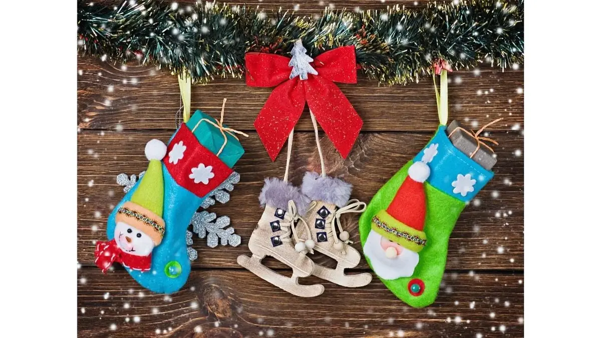 Dziecięce skarpetki z prezentami, pomiędzy nimi wisi ozdoba świąteczna.