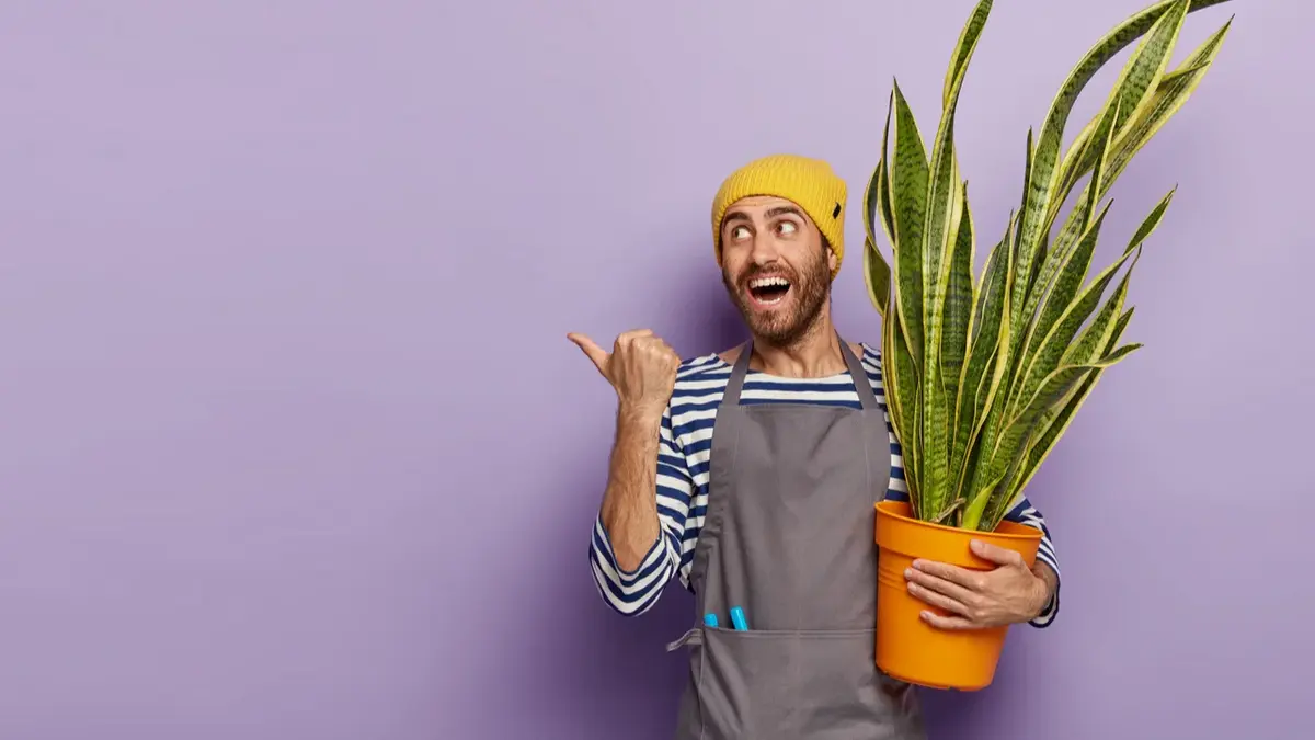 Mężczyzna w czapce z zadowoloną miną trzyma na ręku dużą wężownicę