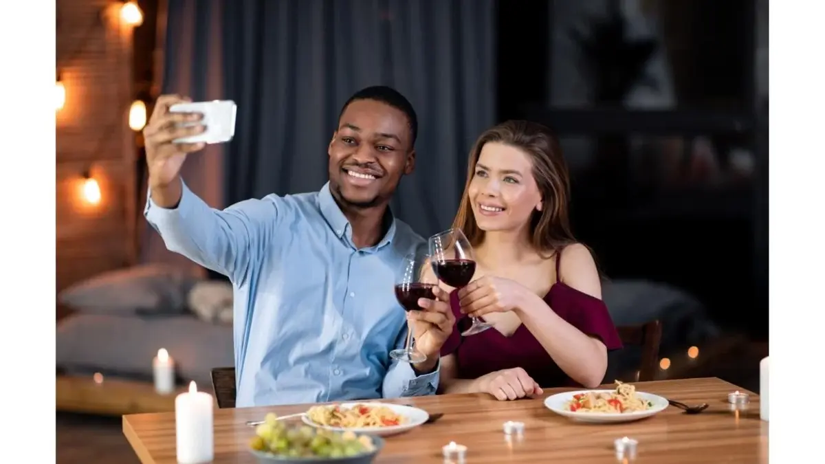 Mężczyzna i kobieta robią sobie selfie podczas romantycznej kolacji.