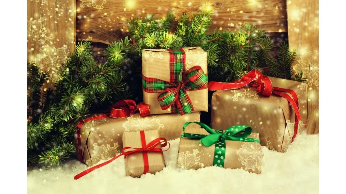 Prezenty gwiazdkowe i iglaste gałęzie leżą na śniegu.