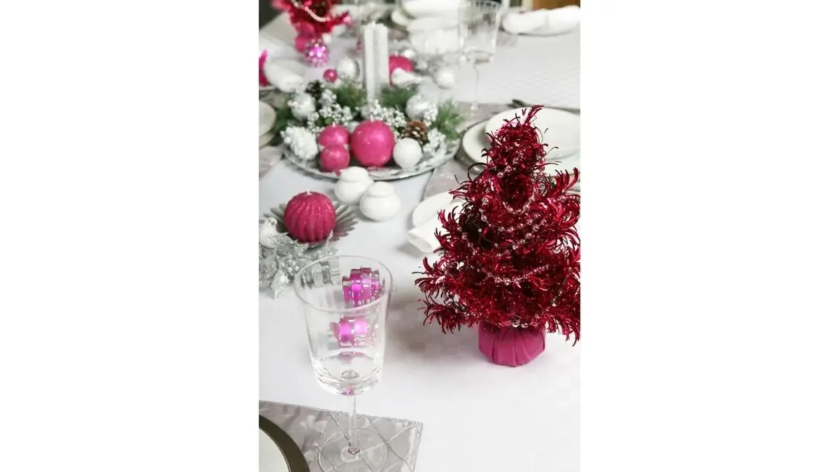 Stół nakryty świątecznie. fioletowa mini choinka i bombki.