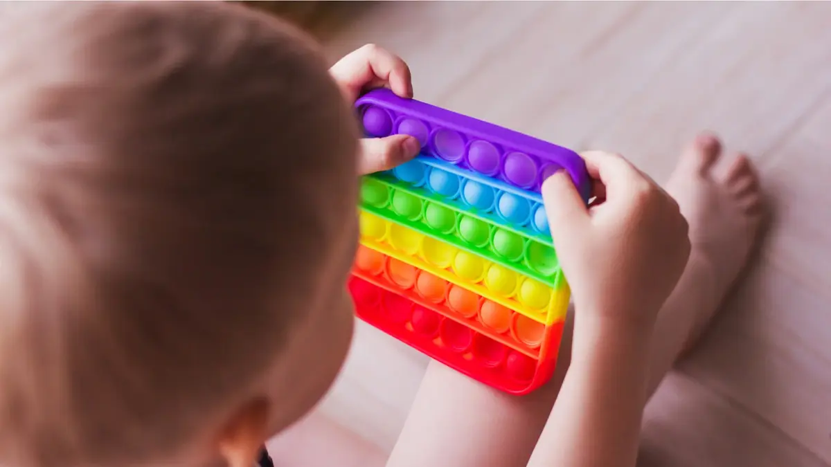 Małe dziecko bawiące się kolorową tęczową zabawką sensoryczną
