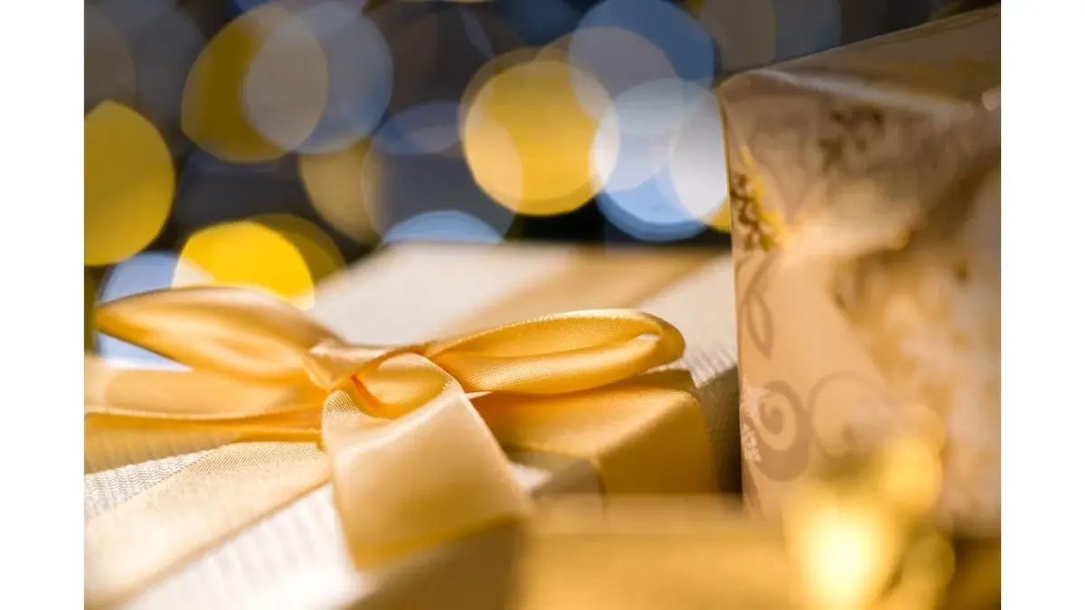 Prezenty w złotych pudełkach otoczone światełkami.