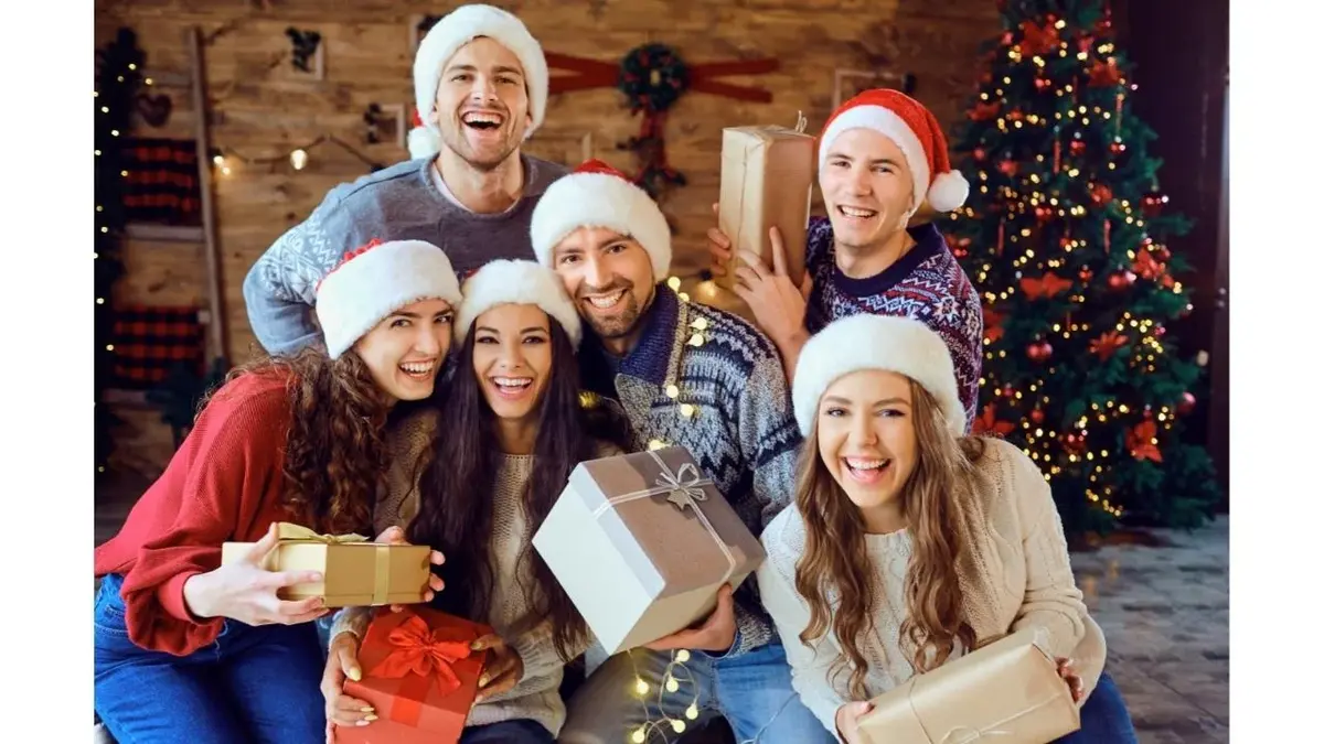 Grupa znajomych w czapakch mikołaja, z prezentami.
