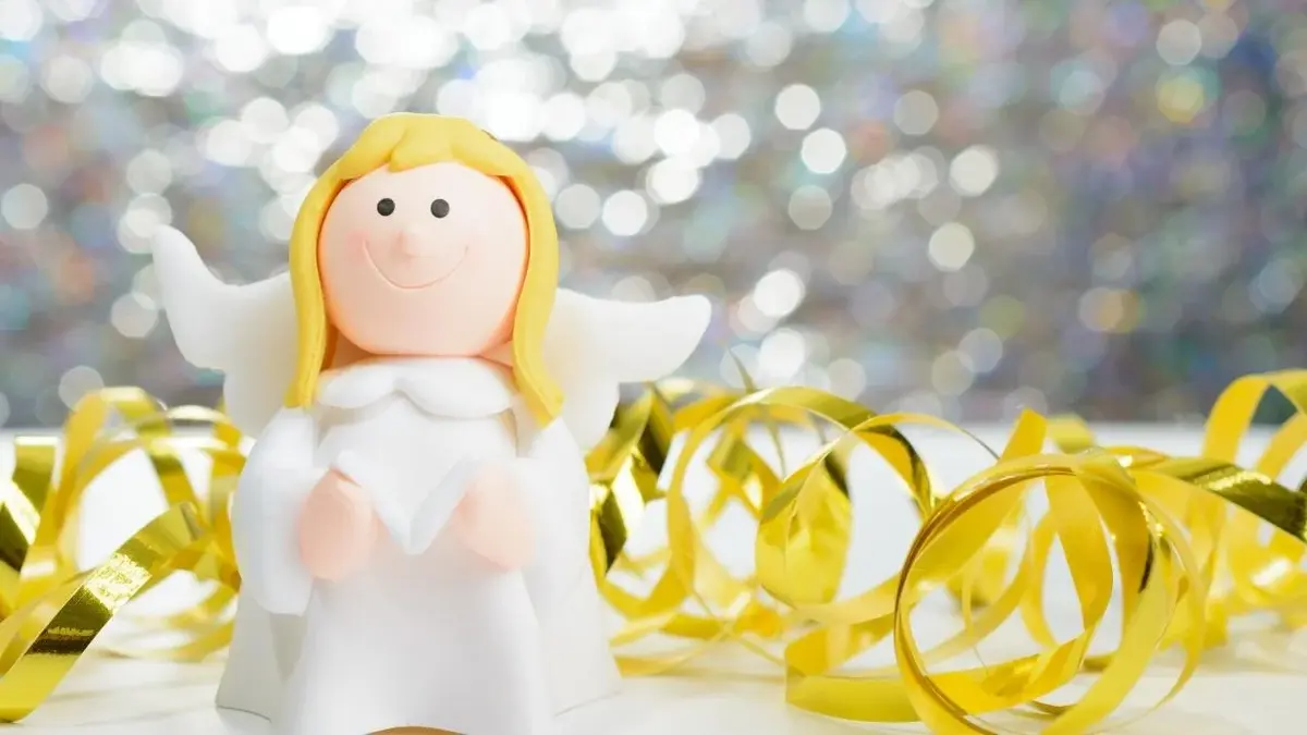 Uśmiechnięty aniołek trzyma śpiewnik z kolędami.