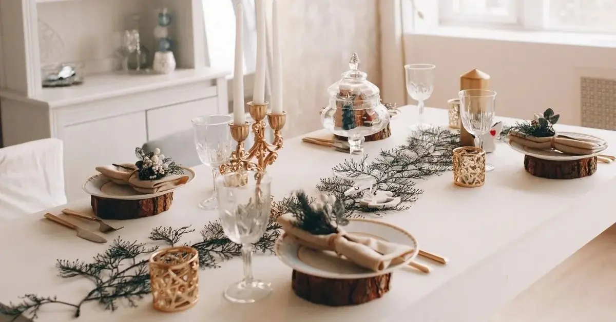 Nakryty białym obrusem stół. na który, stoją białe naczynia i złote dodatki