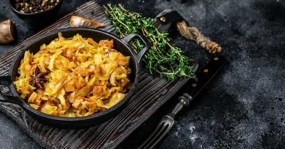 Bigos na czarnym półmisku stojącym na czarnym rustykalnym stole