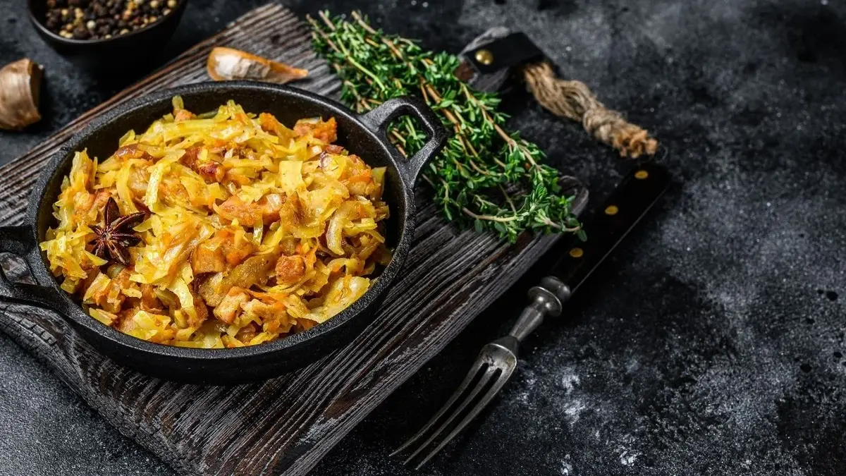 Bigos na czarnym półmisku stojącym na czarnym rustykalnym stole