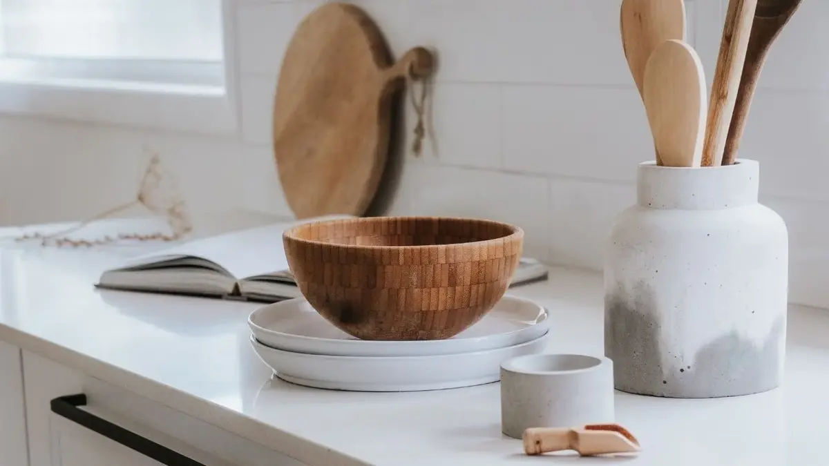 Ceramiczne i drewniane naczynia stojące na białym blacie w kuchni