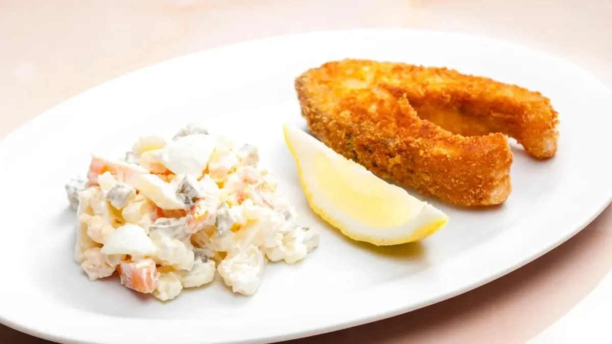 Karp smażony z sałatką jarzynowa i cytryną.