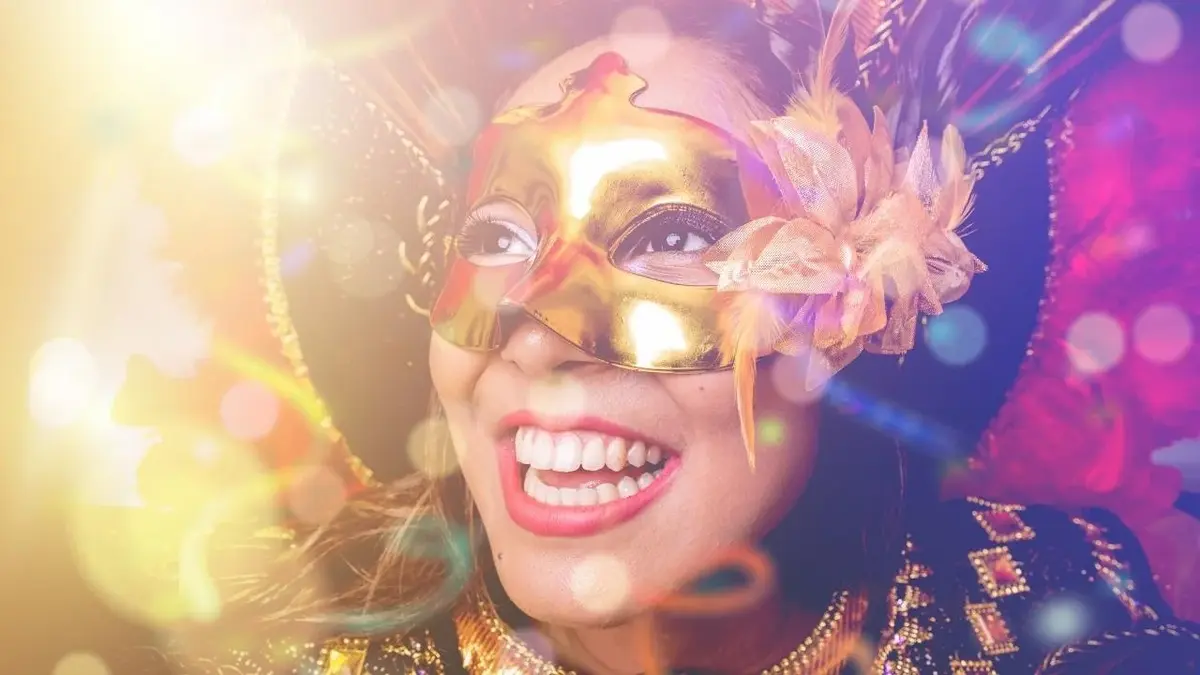 Uśmiechnięta kobieta w masce i stroju karnawałowym.