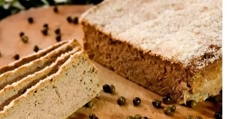 Plasterki pasztetu leżą na desce razem z papryczkami i ziarnami pieprzu