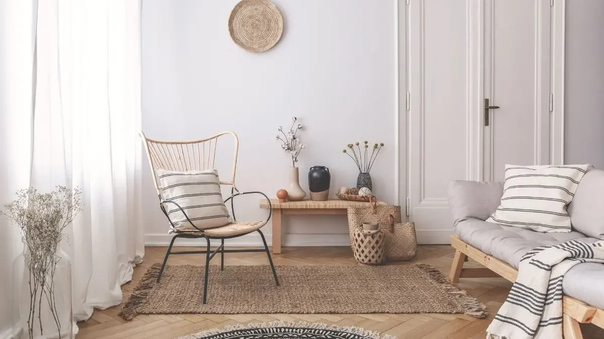 Salon japandi z drewnianą ławą, szarą kanapą i wyplatanym krzesłem