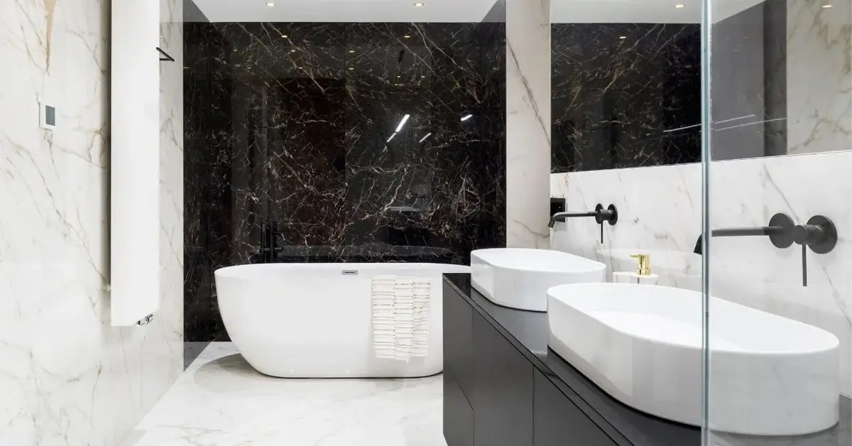 Łazienka z biało-czarnymi marmurowymi płytkami , białą wanną i dwoma białymi umywalkami