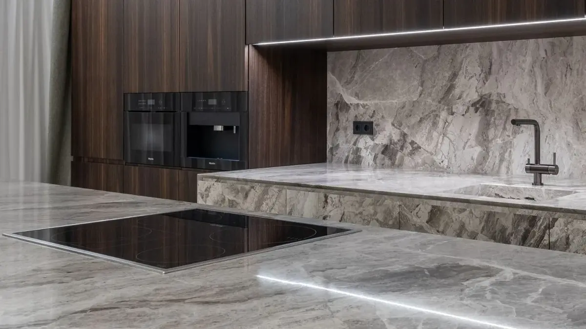 Szara marmurowa kuchnia z brązowymi drewnianymi szafkami