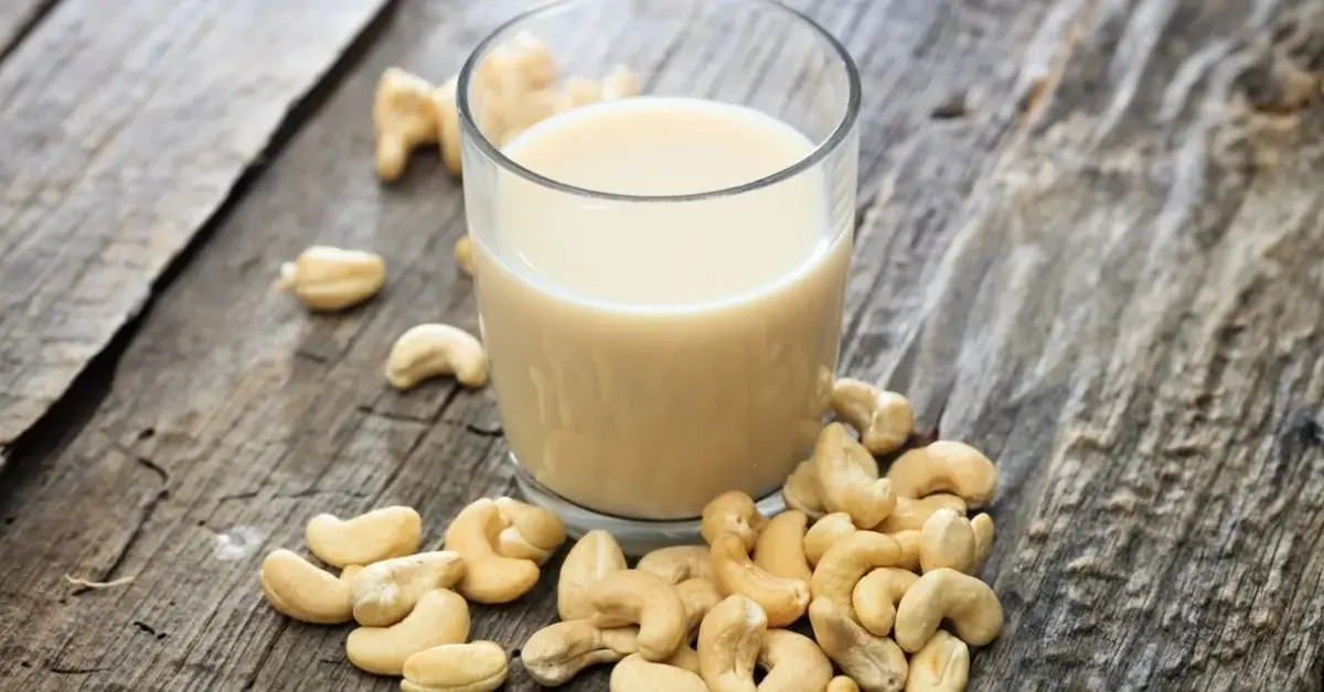 szklanka mleka z orzechów nerkowca i nerkowce rozsypane obok niej