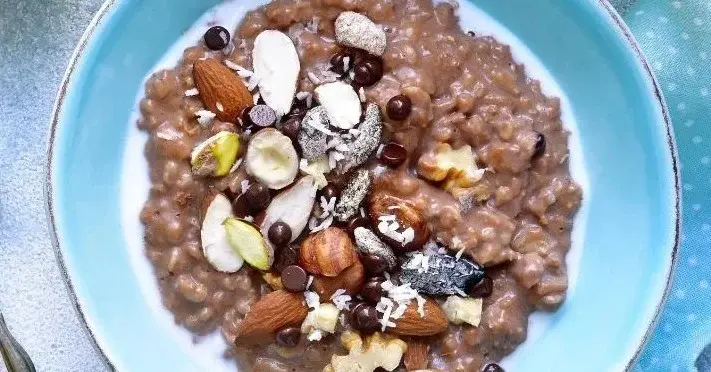 Owsianka czekoladowa udekorowana orzechami i czekoladowymi drażetkami.