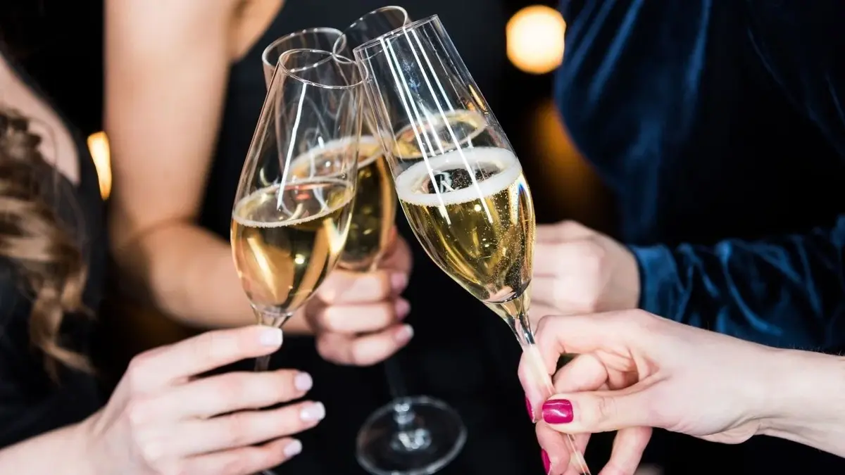 Trzy osoby wznoszą toast kieliszkami z szampanem