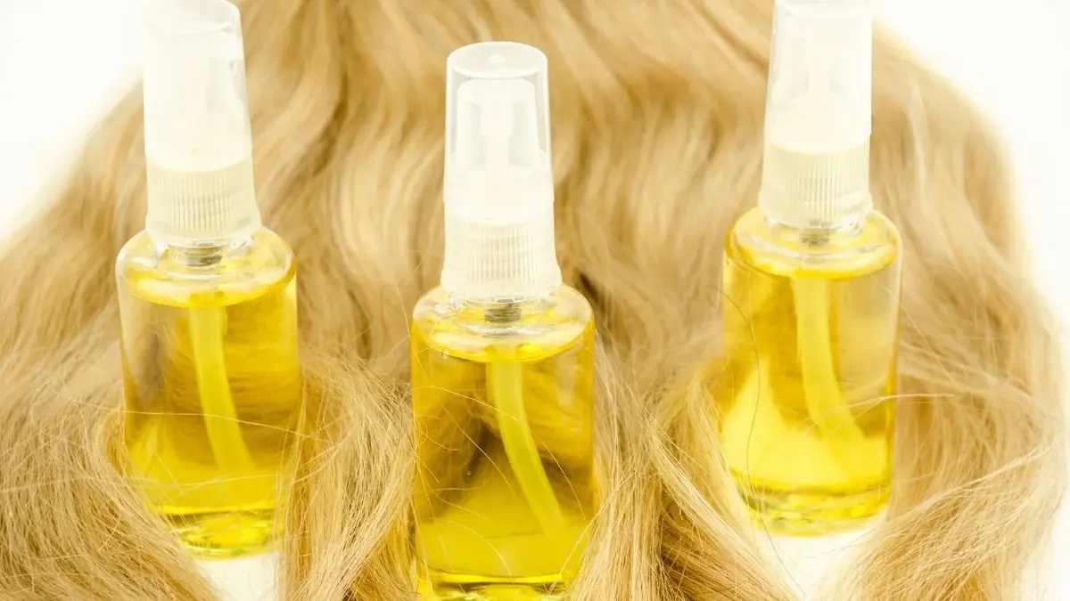 Trzy buteleczki olejku stoją na blond włosach