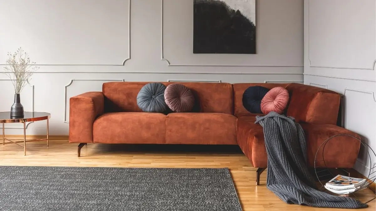 Sofa z weluru w rdzawym kolorze i okrągłe welurowe poduszki