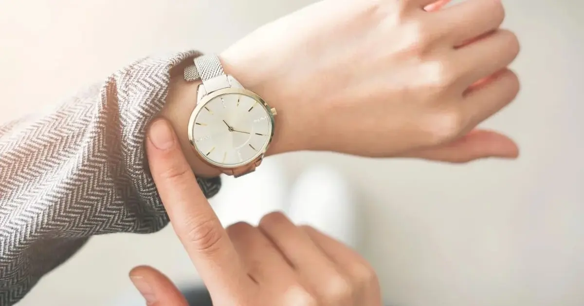 Dłoń z oryginalnym zegarkiem z białą tarczą zegarową