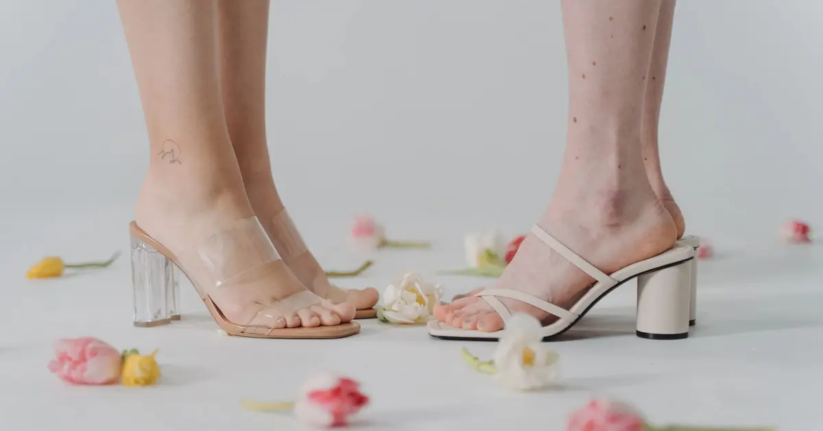 Dwie pary kobiecych stóp w białych sandałach