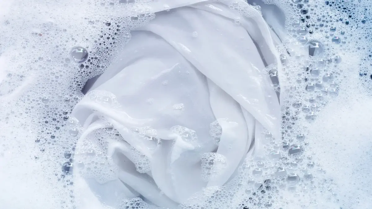 Biała tkanina namoczona w misce w wodzie z mydlinami.