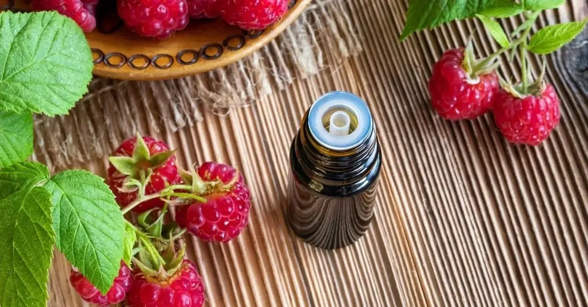 Ciemna buteleczka z olejem z pestek malin. Dookoła leżą maliny.