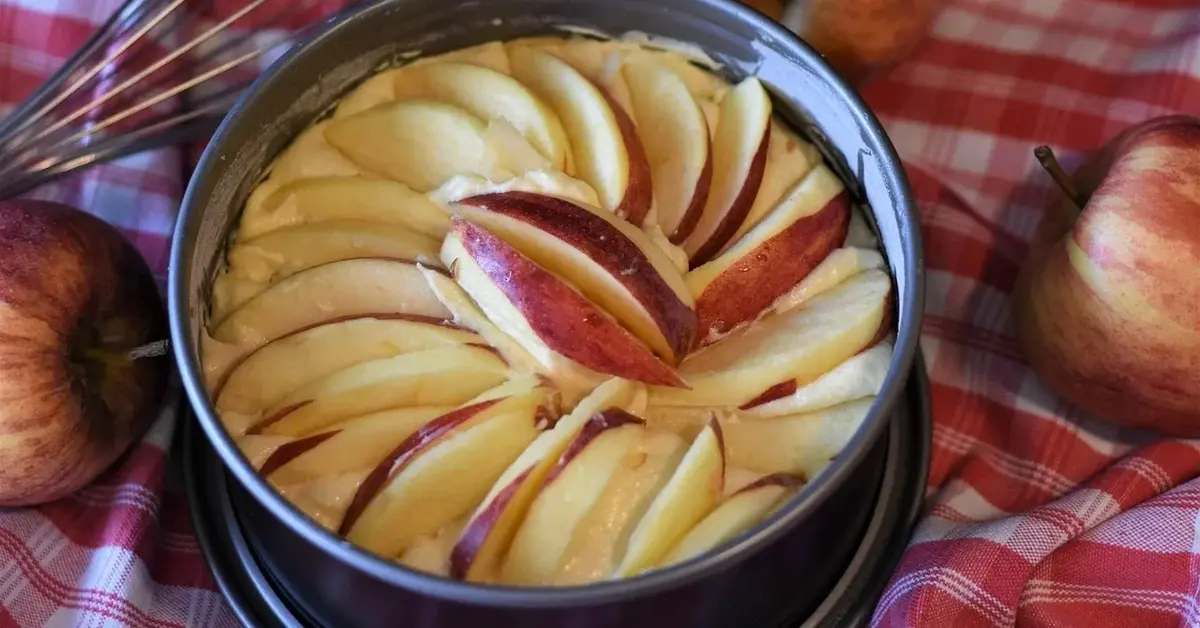 Najłatwiejsze ciasto z jabłkami - ciasto i surowe jabłka w tortownicy przed wstawieniem do piekarnika