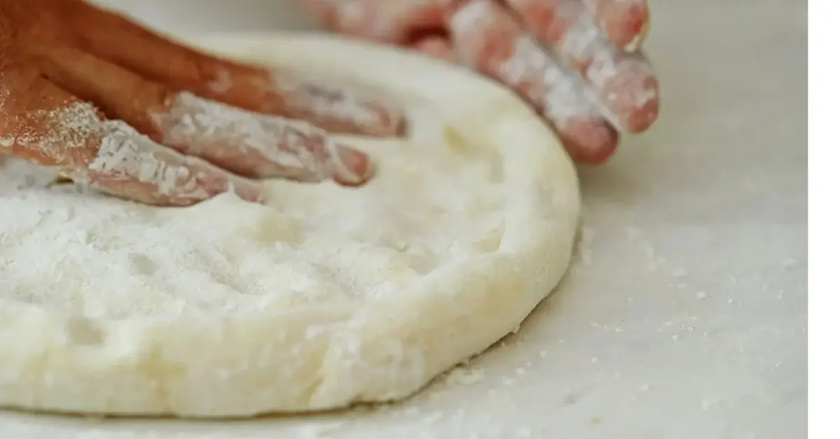 dłonie zagniatające ciasto na pizzę
